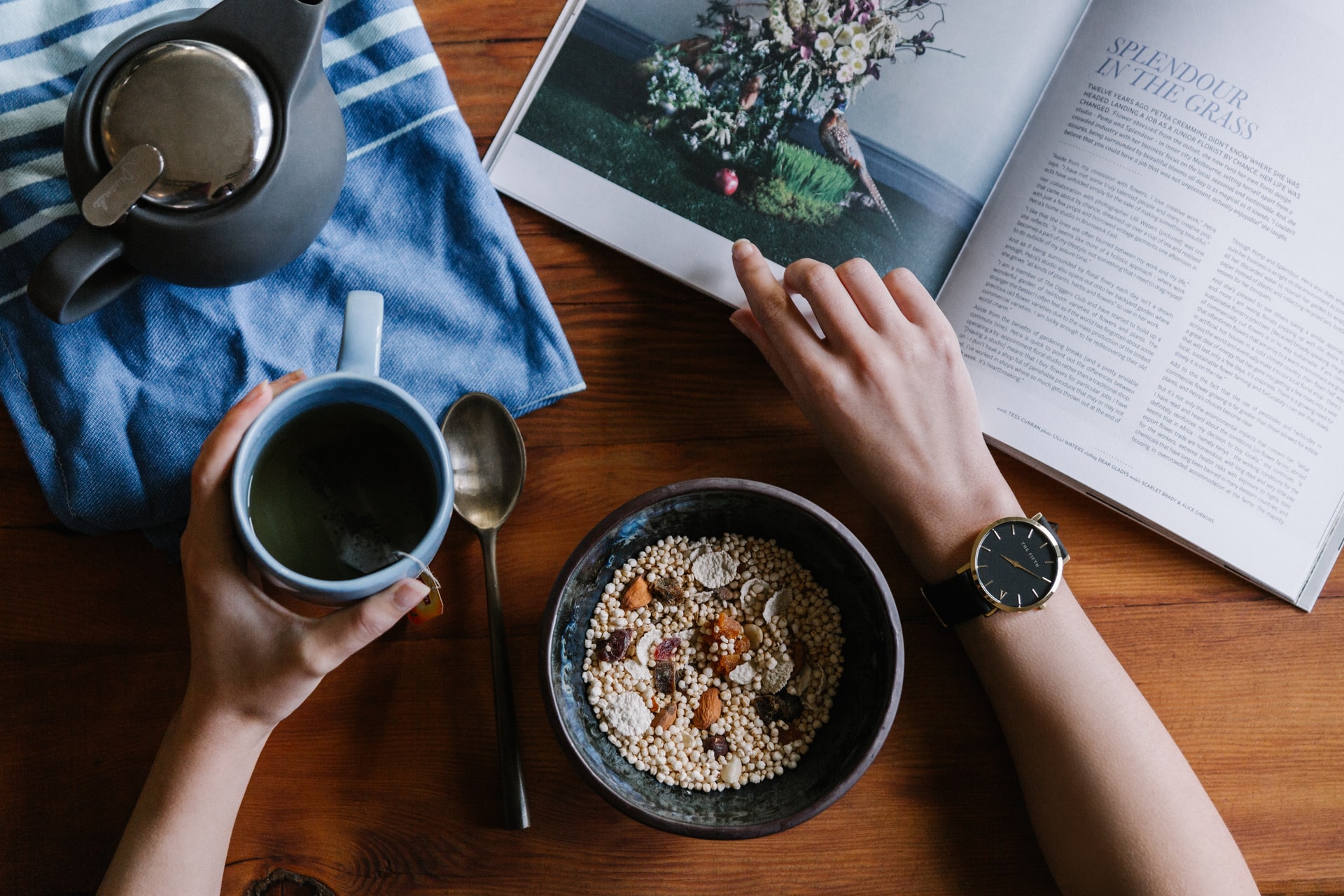 Self-care resolutions blog - overview of breakfast table, coffee mug in left hand, bowl of museli in front and magazine above.