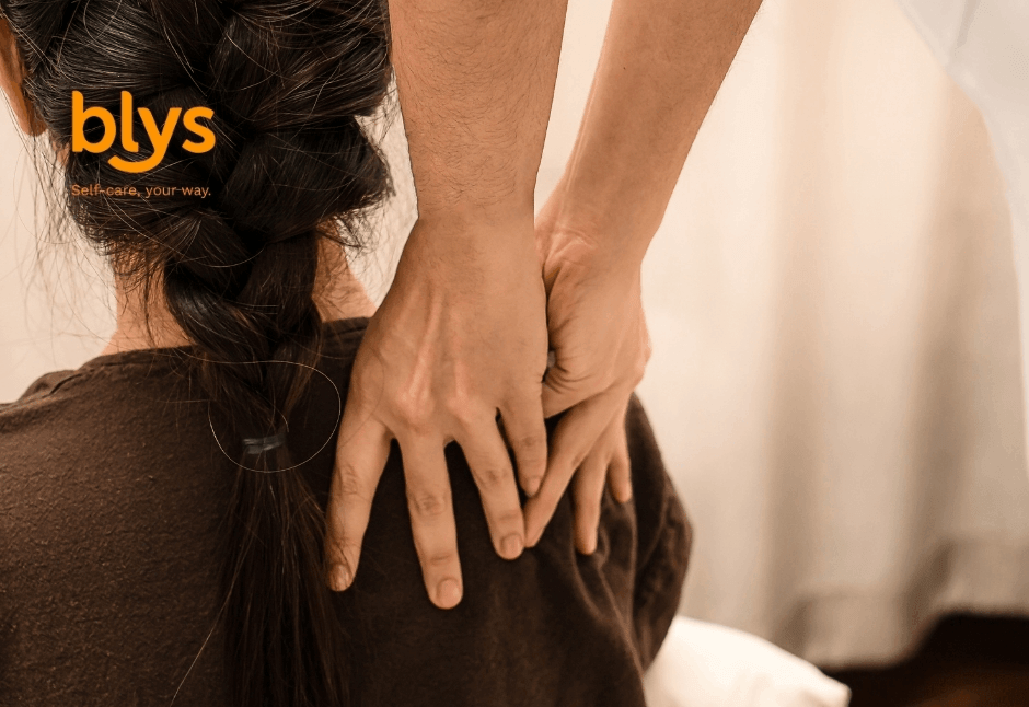 Person receiving a soothing Thai massage, with two hands pressing the shoulders; warm, calming scene promoting relaxation and wellness.