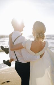 Couple in the beach with the bride wearing a classic low chignon hairstyle