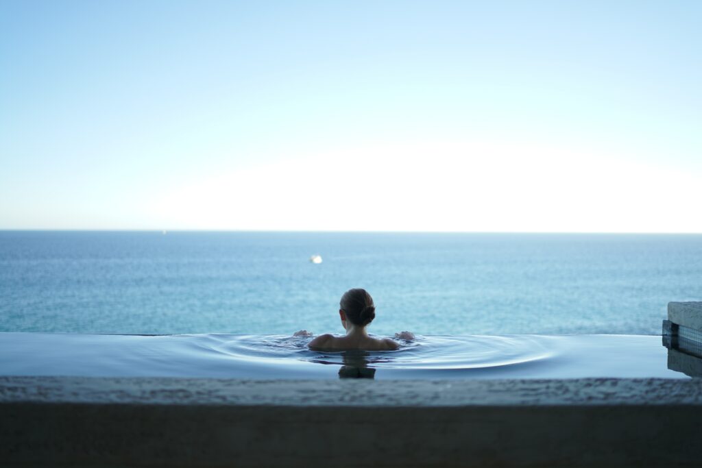 Self-care trends - wellness tourism - woman in infinity pool overlooking the ocean