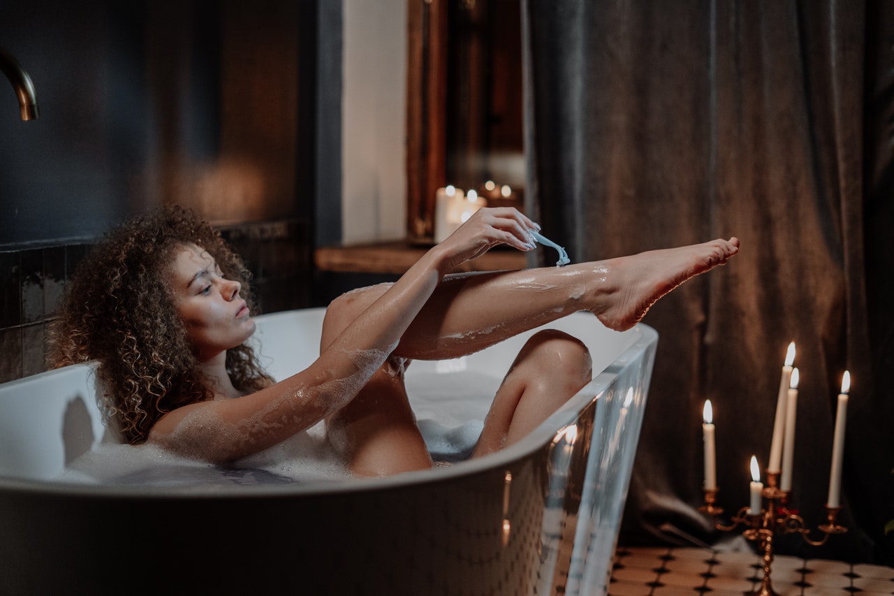 woman shaving legs in the bath tub