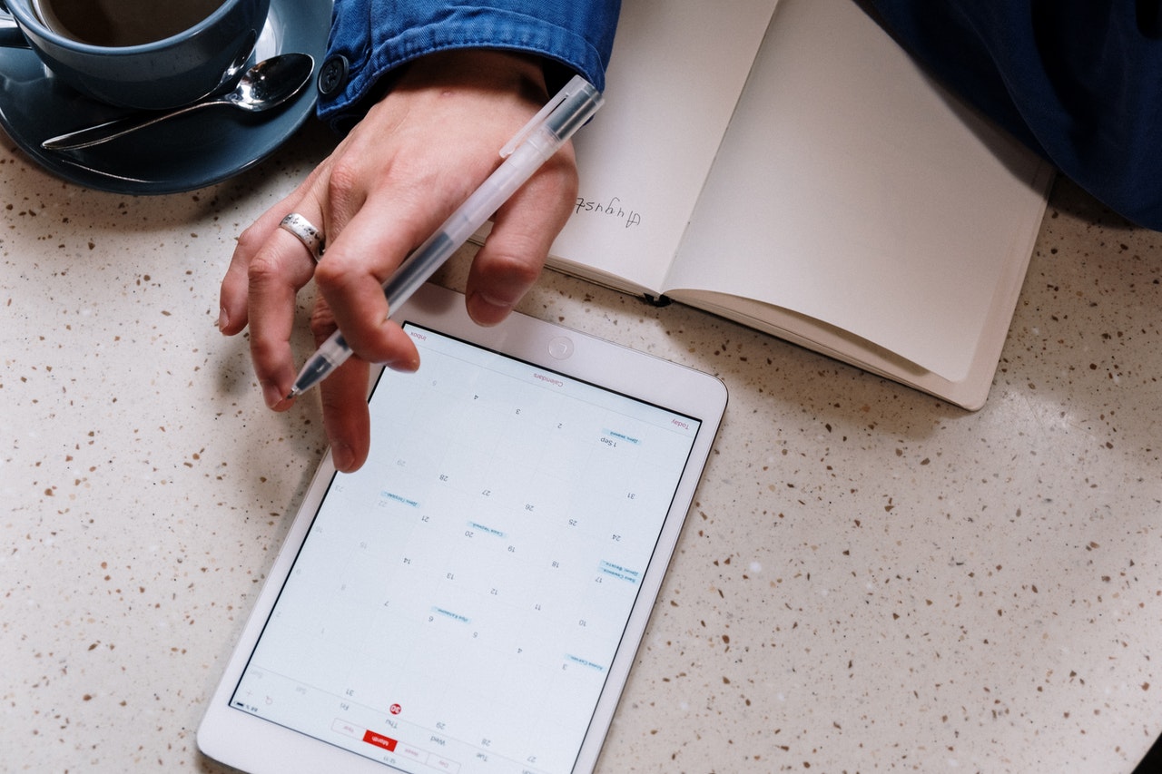 person-holding-pen-and-using-a-tablet