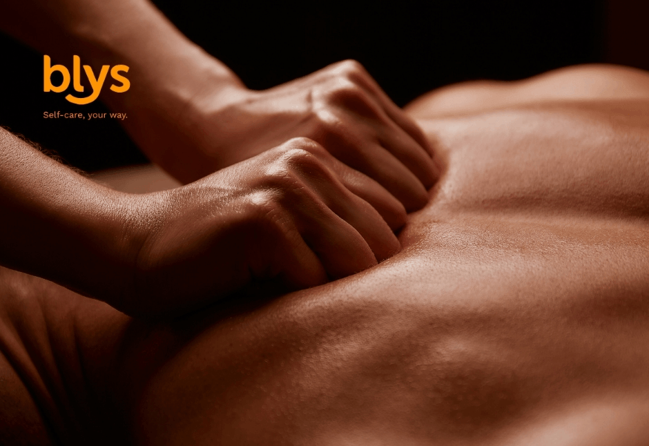 Close-up of hands giving a relaxing back massage in warm, low light; orange “blys” logo and “Self-care, your way” slogan appear at upper left.