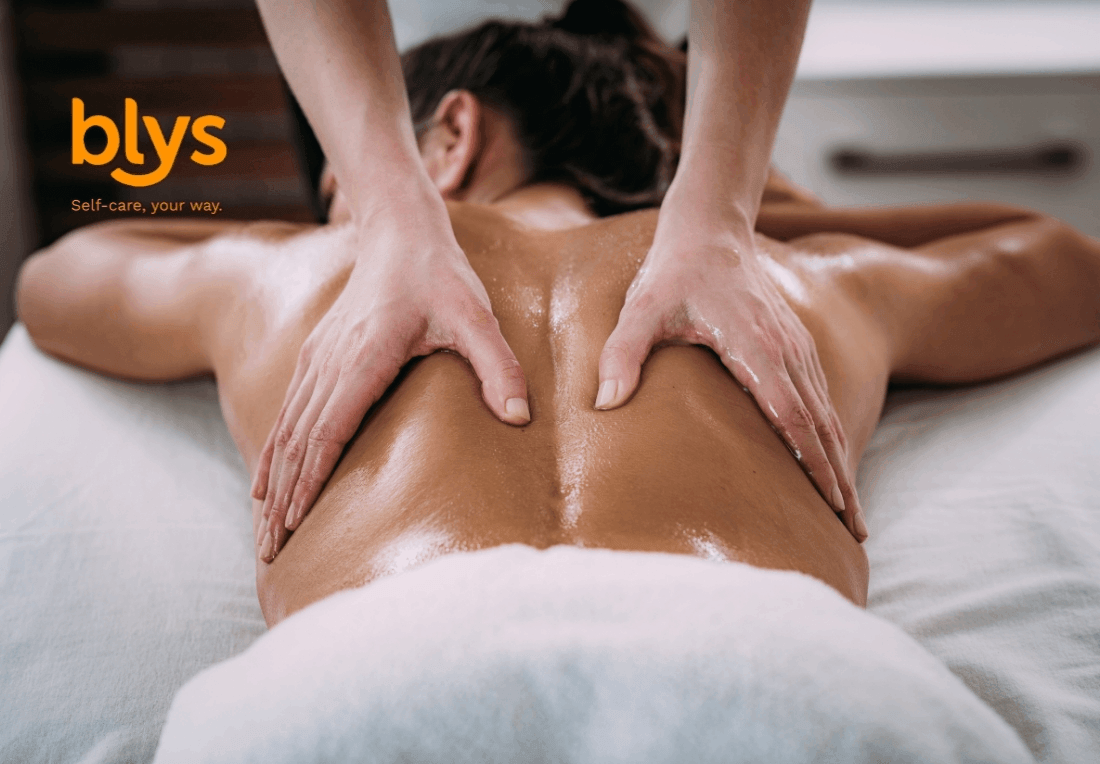 A client lies face down for a relaxing lomi lomi massage, with an oil-slicked back, therapist’s hands, and white towel in a spa setting.